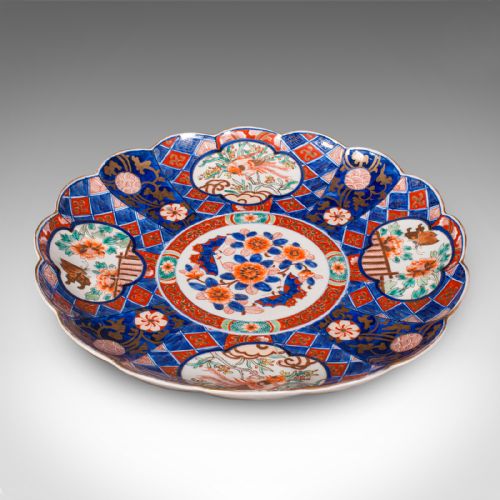 fig 1. A large circular Japanese Imari porcelain charger featuring a scalloped rim, hand-painted cobalt blue and iron-red floral motifs, and gilded accents.