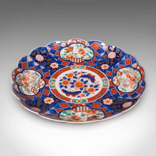 fig 2. A large circular Japanese Imari porcelain charger featuring a scalloped rim, hand-painted cobalt blue and iron-red floral motifs, and gilded accents.