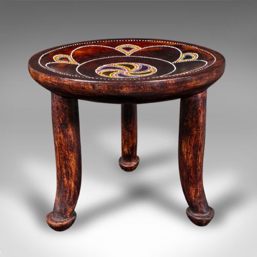 fig 1. A low circular dark fruitwood side table or stool supported by three splayed legs, decorated with colorful beaded swirl patterns across the top.