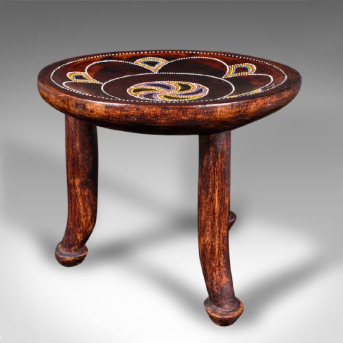 fig 2. A low circular dark fruitwood side table or stool supported by three splayed legs, decorated with colorful beaded swirl patterns across the top.