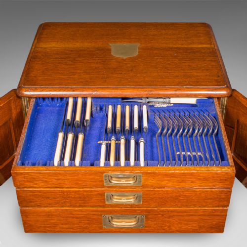 fig 1. An Edwardian oak cutlery canteen featuring double panelled doors, a central key, side flush brass handles, and a top brass shield cartouche.