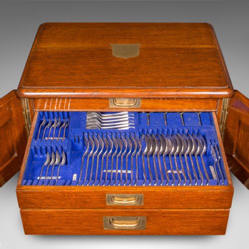 fig 2. An Edwardian oak cutlery canteen featuring double panelled doors, a central key, side flush brass handles, and a top brass shield cartouche.