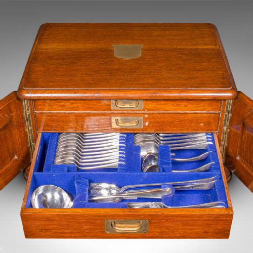 fig 3. An Edwardian oak cutlery canteen featuring double panelled doors, a central key, side flush brass handles, and a top brass shield cartouche.