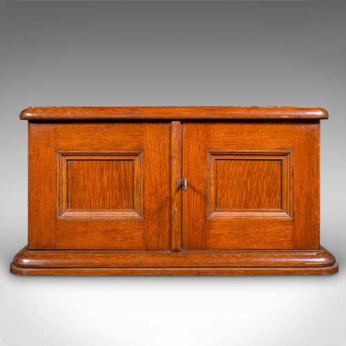 fig 4. An Edwardian oak cutlery canteen featuring double panelled doors, a central key, side flush brass handles, and a top brass shield cartouche.