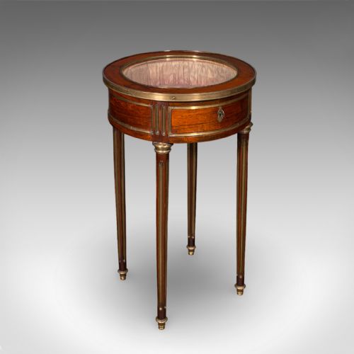 fig 1. An antique French circular bijouterie table crafted from kingwood, featuring fluted legs with brass mounts and an open hinged glazed lid revealing a tufted pink silk interior.