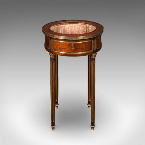 fig 3. An antique French circular bijouterie table crafted from kingwood, featuring fluted legs with brass mounts and an open hinged glazed lid revealing a tufted pink silk interior.
