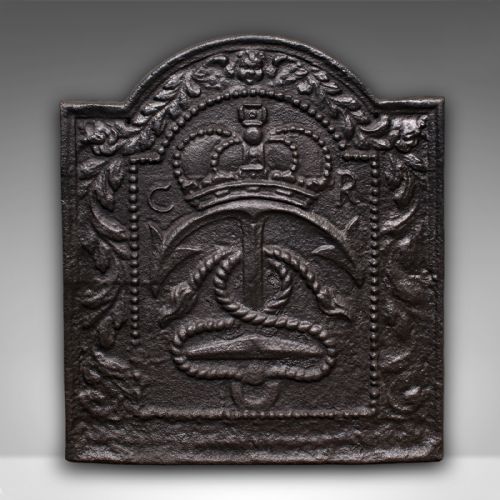 fig 1. An arched cast iron fire back featuring a raised relief design of a royal crown, an anchor with rope, and foliate borders in a dark patinated finish.