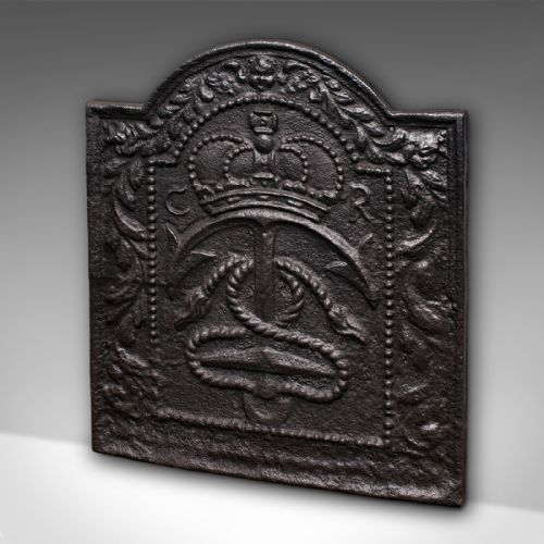 fig 2. An arched cast iron fire back featuring a raised relief design of a royal crown, an anchor with rope, and foliate borders in a dark patinated finish.