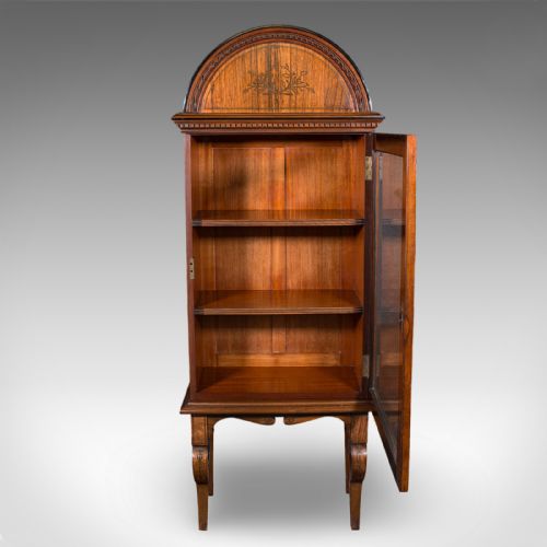 fig 2. A tall Regency oak display cabinet featuring an arched bonnet top with marquetry inlay, a single glazed door enclosing shelves, and carved front legs.