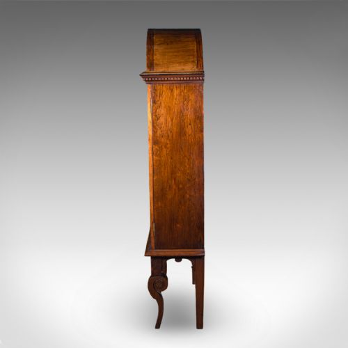 fig 4. A tall Regency oak display cabinet featuring an arched bonnet top with marquetry inlay, a single glazed door enclosing shelves, and carved front legs.