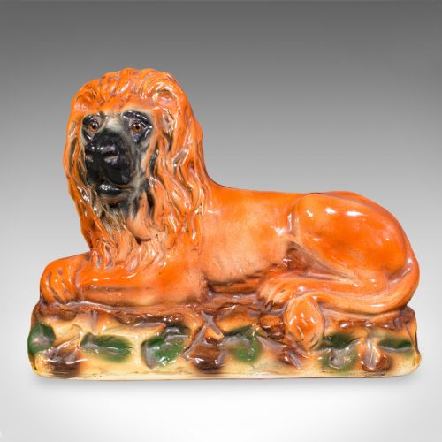 fig 2. A pair of Victorian glazed ceramic recumbent lion bookends in terracotta orange resting on textured green and brown bases.