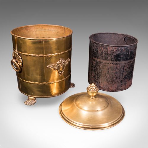 fig 2. A cylindrical brass coal bin featuring a domed lid with a finial, side ring handles, embossed scrollwork, and lion paw feet.