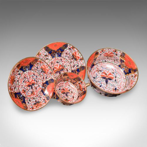 fig 1. A ten-person Victorian bone china tea service decorated with blue, orange, and gold Imari patterns, featuring teacups, saucers, plates, and a waste bowl.