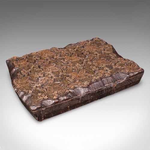 fig 1. A rectangular dark carved wooden printing block set with intricate brass wire and pin work forming a floral motif.