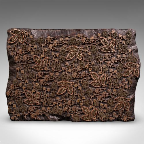 fig 2. A rectangular dark carved wooden printing block set with intricate brass wire and pin work forming a floral motif.