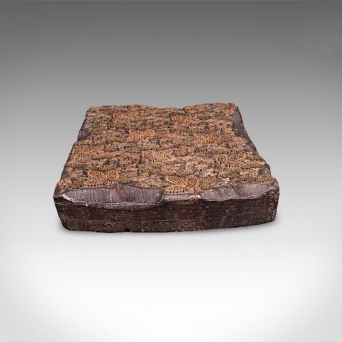 fig 3. A rectangular dark carved wooden printing block set with intricate brass wire and pin work forming a floral motif.