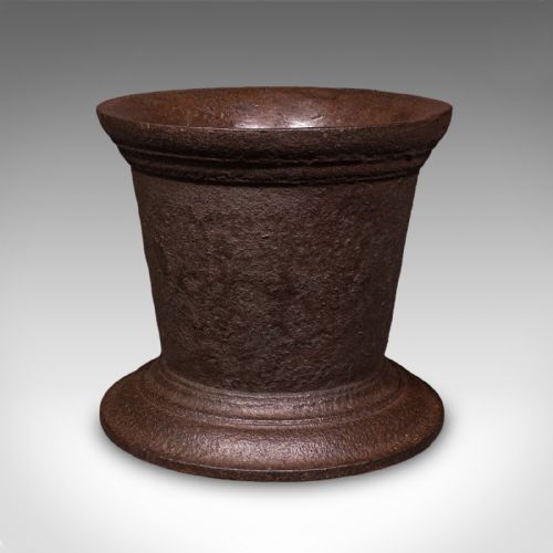 fig 2. A large Georgian cast iron mortar with a flared rim and stepped pedestal base, accompanied by a solid iron pestle.