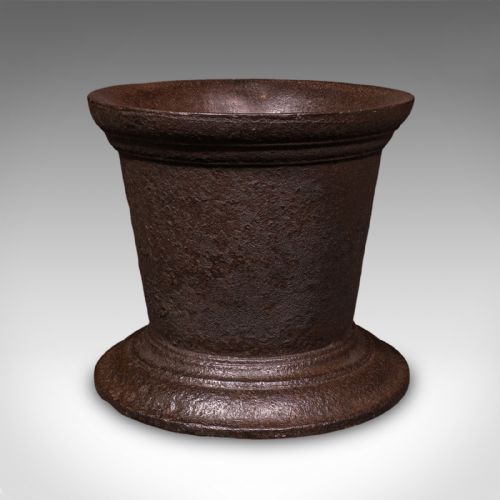 fig 3. A large Georgian cast iron mortar with a flared rim and stepped pedestal base, accompanied by a solid iron pestle.
