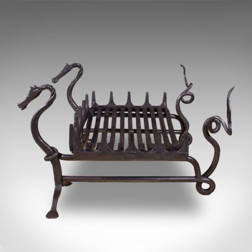 fig 3. A black hand-forged wrought iron fire basket featuring a curved slatted grate supported by four legs with dragon head and tail terminals.