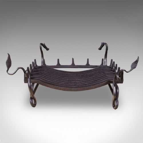 fig 5. A black hand-forged wrought iron fire basket featuring a curved slatted grate supported by four legs with dragon head and tail terminals.