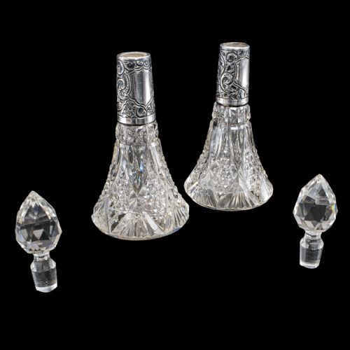 fig 1. A pair of conical cut crystal scent bottles featuring embossed silver collars and faceted glass stoppers.