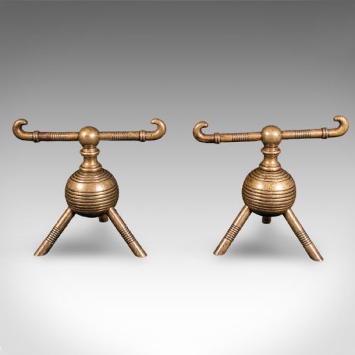 fig 1. A pair of late Victorian brass fireside tool rests featuring ribbed spherical central bodies, tripod legs, and hooked horizontal crossbars.