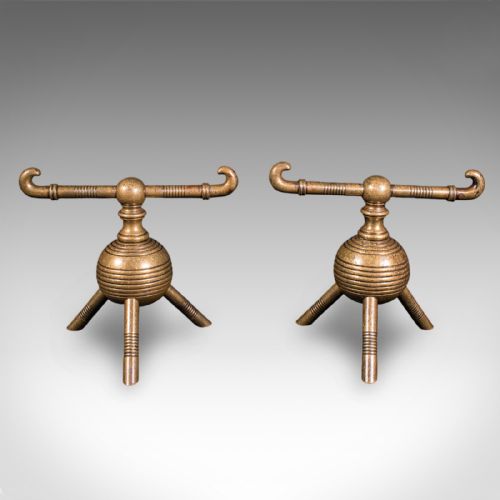 fig 4. A pair of late Victorian brass fireside tool rests featuring ribbed spherical central bodies, tripod legs, and hooked horizontal crossbars.