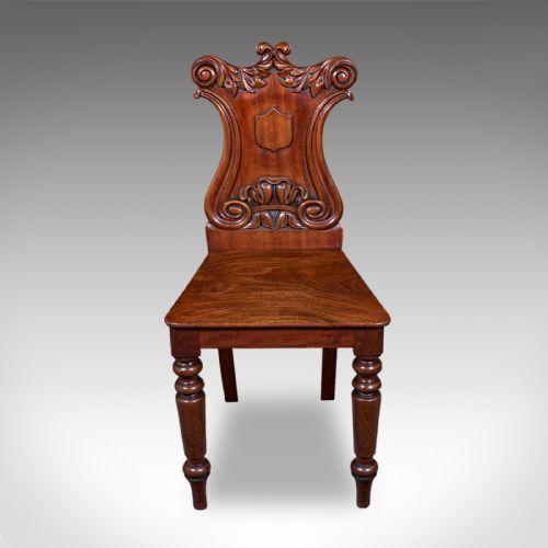 fig 1. A Victorian mahogany hall chair featuring a relief-carved shield backrest, scroll accents, a solid timber seat, and turned front legs.