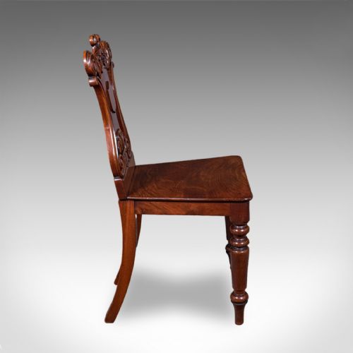 fig 2. A Victorian mahogany hall chair featuring a relief-carved shield backrest, scroll accents, a solid timber seat, and turned front legs.