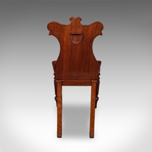 fig 3. A Victorian mahogany hall chair featuring a relief-carved shield backrest, scroll accents, a solid timber seat, and turned front legs.