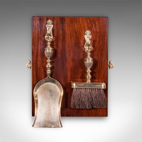 fig 3. A wall-mounted Regency period brass hearth set featuring a shovel and brush hanging from turned brass hooks on a polished mahogany board.