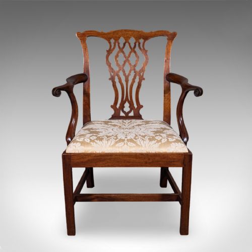 fig 1. An antique Georgian mahogany elbow chair featuring a carved pierced splat back, swept arms, and a cream patterned upholstered seat.