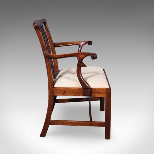 fig 2. An antique Georgian mahogany elbow chair featuring a carved pierced splat back, swept arms, and a cream patterned upholstered seat.