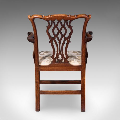 fig 3. An antique Georgian mahogany elbow chair featuring a carved pierced splat back, swept arms, and a cream patterned upholstered seat.