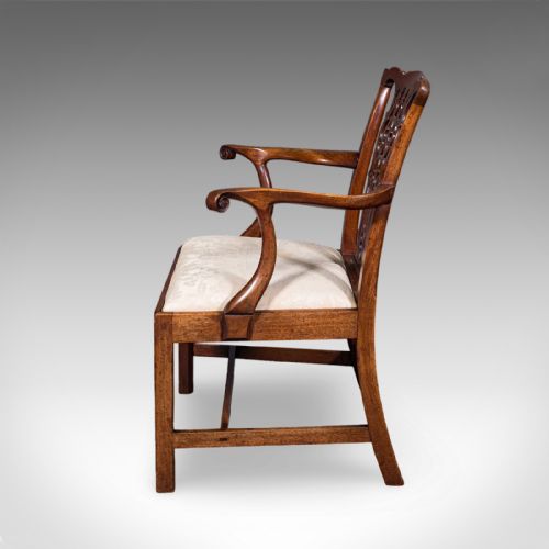 fig 4. An antique Georgian mahogany elbow chair featuring a carved pierced splat back, swept arms, and a cream patterned upholstered seat.