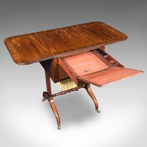 fig 2. A Regency mahogany drop-leaf sewing table with three drawers, a pleated cream fabric work basket, and swept legs on brass castors.