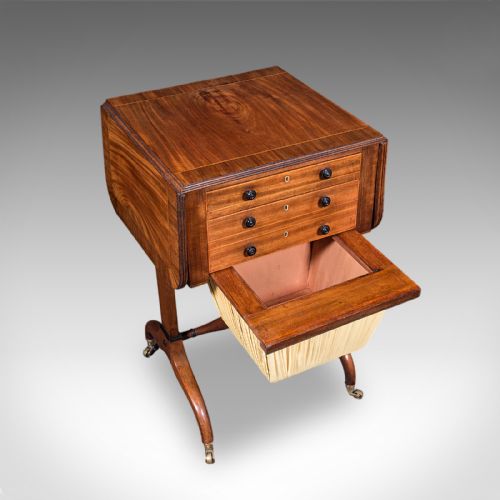 fig 4. A Regency mahogany drop-leaf sewing table with three drawers, a pleated cream fabric work basket, and swept legs on brass castors.