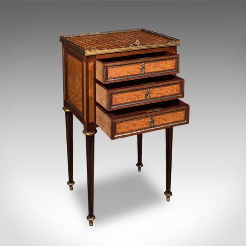 fig 1. A French Louis XVI Revival walnut bedside table with three marquetry drawers, a brass gallery rim, and tapered legs.