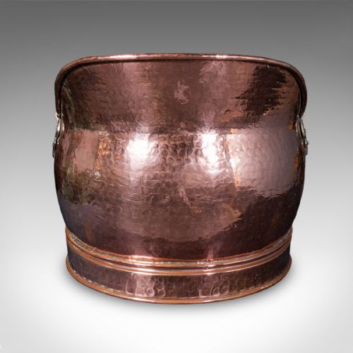 fig 1. An antique Victorian hand-hammered copper coal scuttle featuring a raised rear lip, rolled rim, and an overhead brass swing handle.