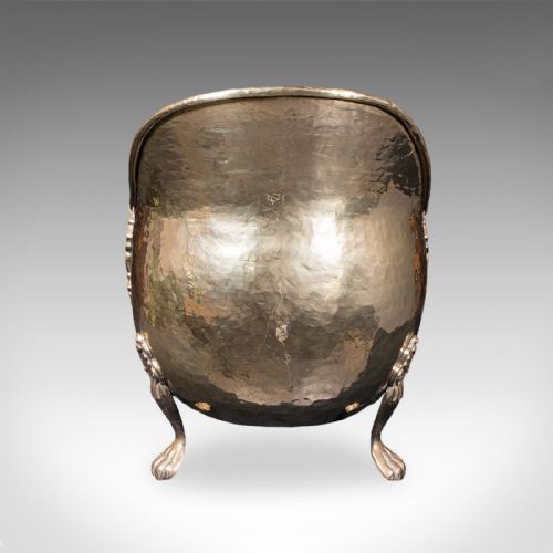 fig 1. An antique English Regency brass coal scuttle featuring a hand-hammered texture, an arched handle, and cast claw feet.