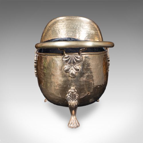 fig 3. An antique English Regency brass coal scuttle featuring a hand-hammered texture, an arched handle, and cast claw feet.