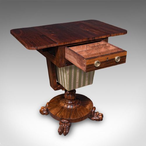 fig 1. A William IV dark rosewood drop-leaf sewing table featuring a top drawer, a fabric work basket below, and a carved pedestal base with paw feet.