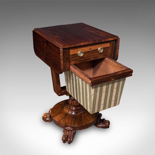 fig 2. A William IV dark rosewood drop-leaf sewing table featuring a top drawer, a fabric work basket below, and a carved pedestal base with paw feet.