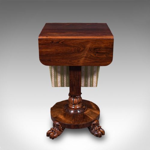 fig 4. A William IV dark rosewood drop-leaf sewing table featuring a top drawer, a fabric work basket below, and a carved pedestal base with paw feet.