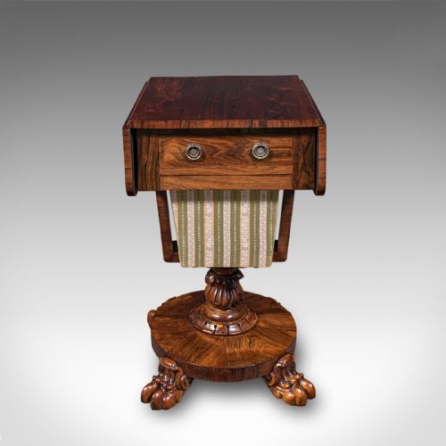 fig 5. A William IV dark rosewood drop-leaf sewing table featuring a top drawer, a fabric work basket below, and a carved pedestal base with paw feet.