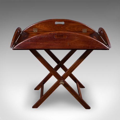 fig 2. An Edwardian mahogany butlers tray table featuring an oval top with fold-down flaps, brass flush hinges, cut-out carrying handles, and a folding X-frame base.
