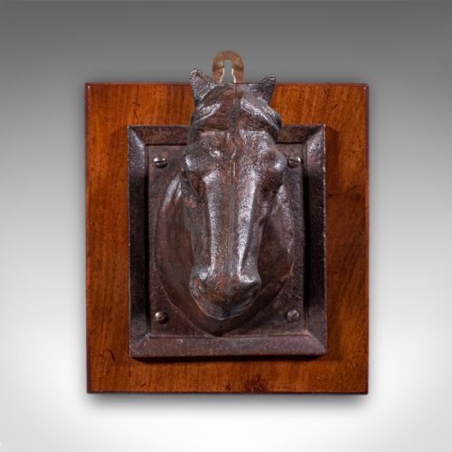 fig 1. A cast iron horse head bust mounted within an iron frame on a square polished wooden plaque.