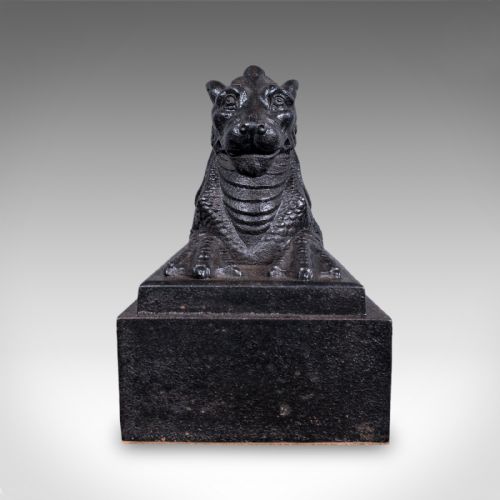 fig 1. A heavy black cast iron doorstop crafted in the form of a reclining guardian lion resting on a stepped rectangular base.