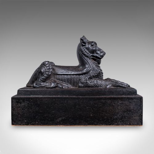 fig 2. A heavy black cast iron doorstop crafted in the form of a reclining guardian lion resting on a stepped rectangular base.