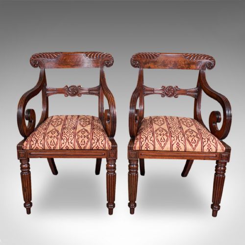 fig 1. A pair of antique William IV mahogany elbow chairs featuring carved crest rails, sweeping scroll arms, fluted turned front legs, and patterned upholstery.